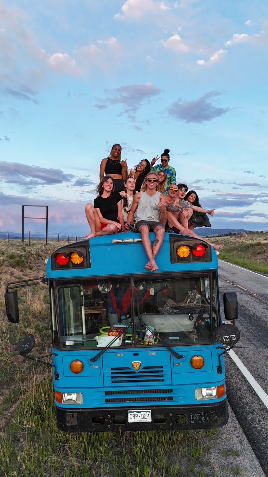 Theo and friends sitting on top of the blue school bus beneath an open sky